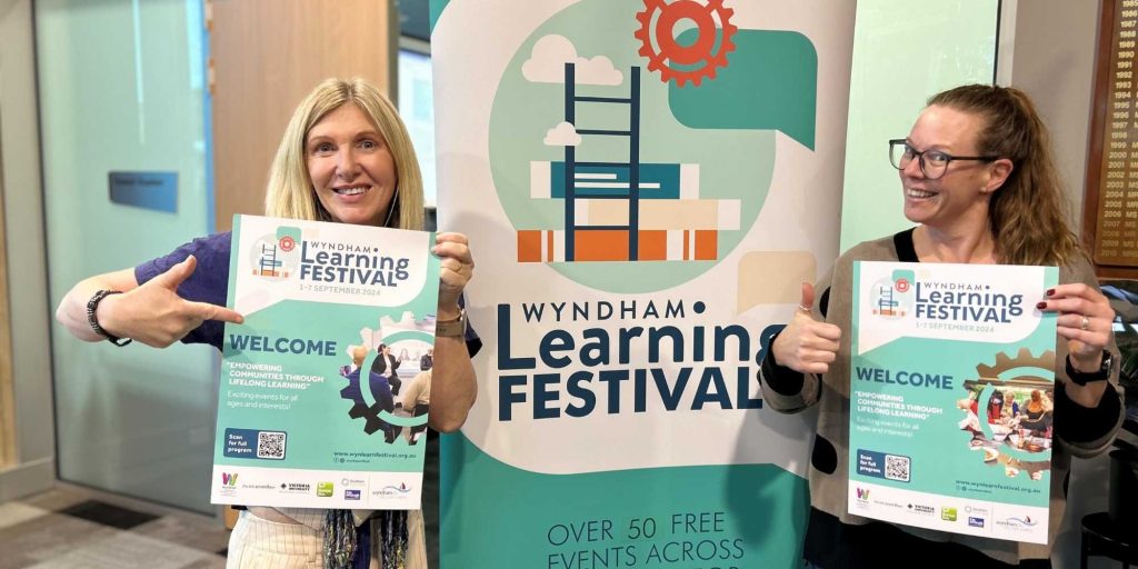 Learning Festival team in from of WLF banner holding welcome posters